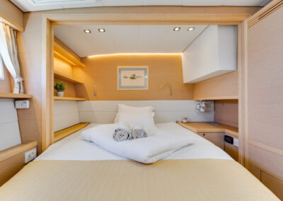 A luxurious bedroom on the Lagoon 560 s2 catamaran, with a king-size bed, wooden furnishings.