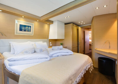 A luxurious bedroom on the Lagoon 560 s2 catamaran, with a king-size bed, wooden furnishings.