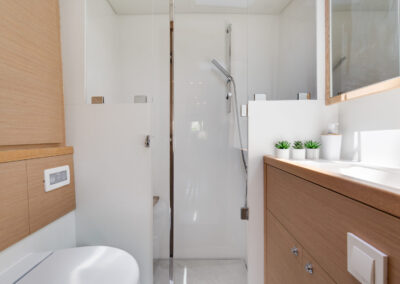 A modern and well-appointed bathroom on the Lagoon 560 catamaran. The bathroom features a spacious shower, a vanity with a sink, and ample storage space.