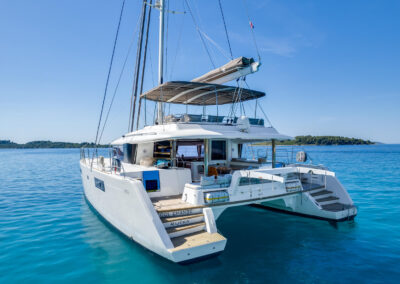 Side rear view of the Lagoon 560 catamaran, anchored in the crystal-clear sea of Croatia.