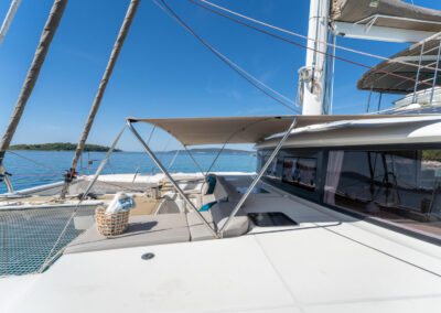 A view of the spacious deck of the Lagoon 560 catamaran. The comfortable seating area, sunshade, and stunning sea view create the perfect setting for relaxation and enjoyment. This luxurious yacht is ideal for a memorable sailing holiday in Croatia.