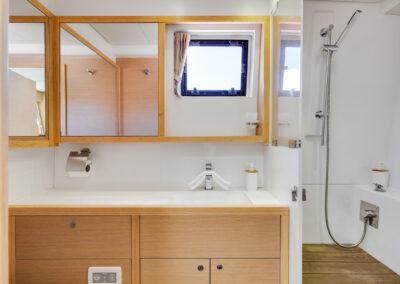 A modern and well-appointed bathroom on the Lagoon 560 catamaran. The bathroom features a spacious shower, a vanity with a sink, and ample storage space.