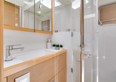 A modern and well-appointed bathroom on the Lagoon 560 catamaran. The bathroom features a spacious shower, a vanity with a sink, and ample storage space.