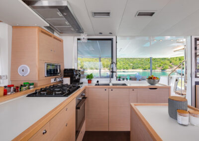 Well equipped kitchen of the Cool Change catamaran, with a beautiful view of the sea and a coastline.