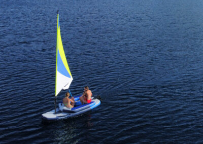 A couple sailing a small inflatable sailboat.