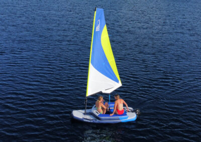 A couple sailing a small inflatable sailboat.