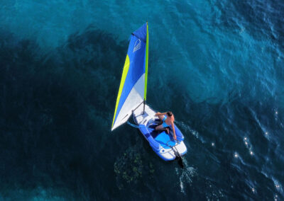 A man sailing a small inflatable sailboat.