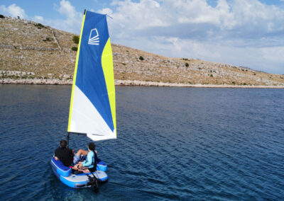 2 people on a sail paddleboard on the blue sea.